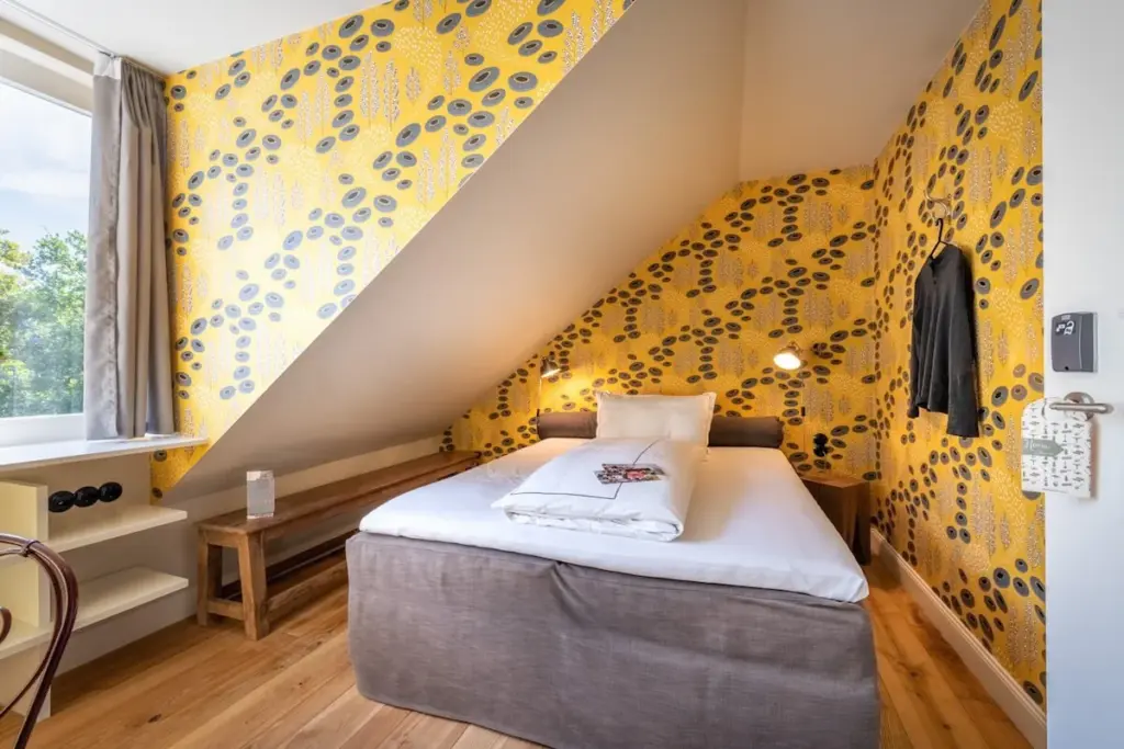 Dachzimmer mit gelber Tapete und Doppelbett