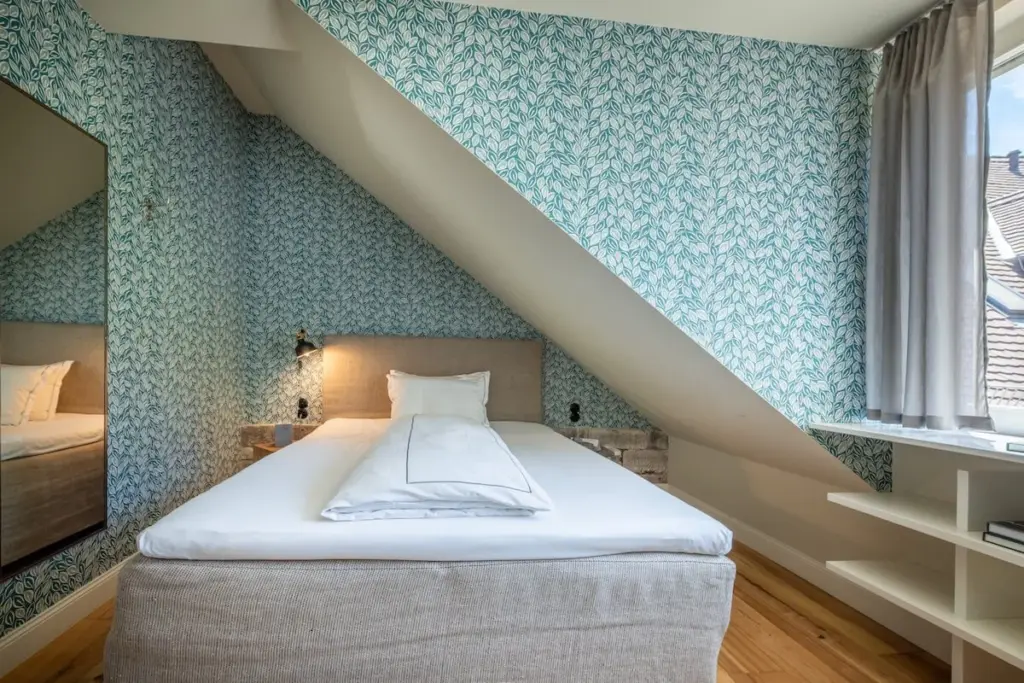 Schlafzimmer mit Bett unter Dachschräge und gemusterter Wand