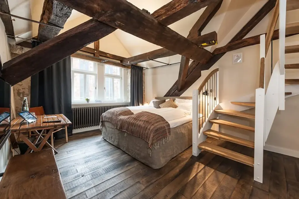 Dachzimmer mit sichtbaren Holzbalken und Bett