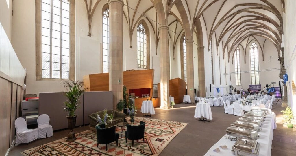 Historischer Saal mit hohen Gewölben und Sitzbereich